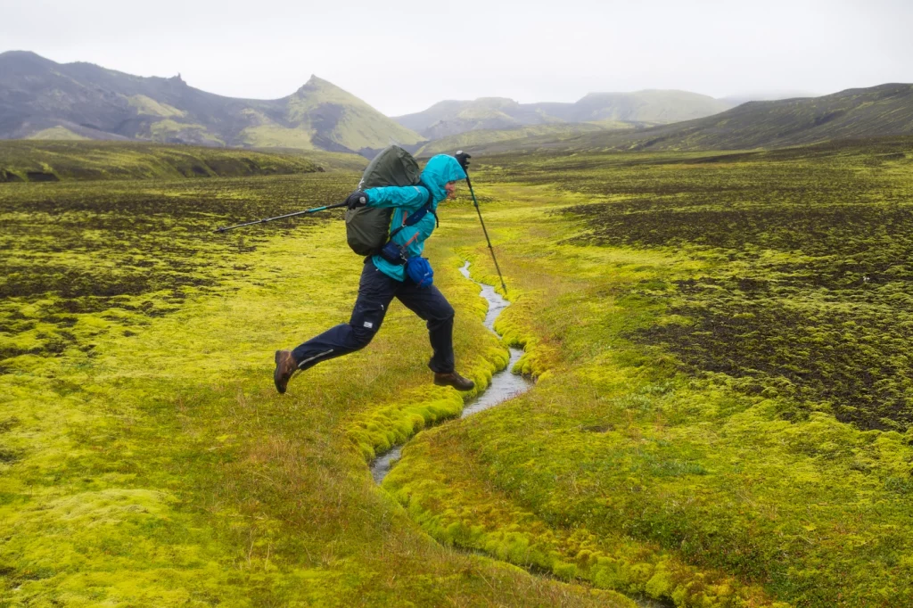 Wanderer springt über kleinen Bach