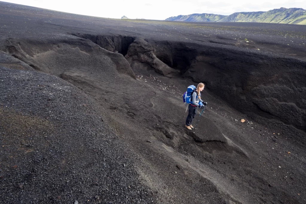Person in schwarzer Geröll-Berglandschaft