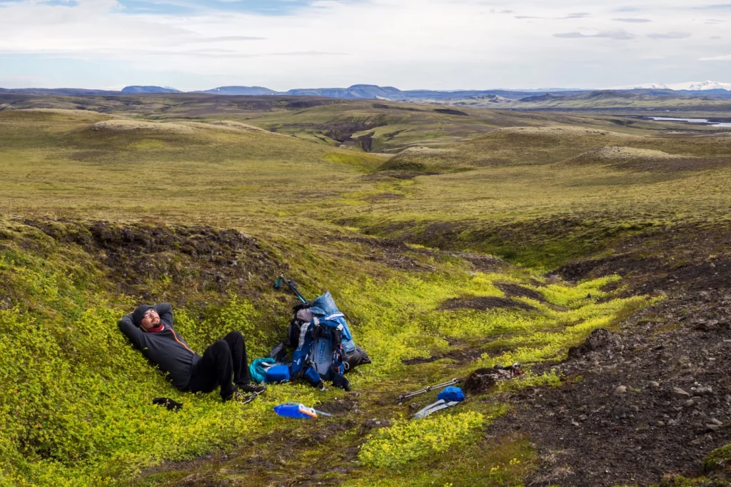 Person liegt in einer Rinne, die mit hellgrünem Gras bewachsen ist
