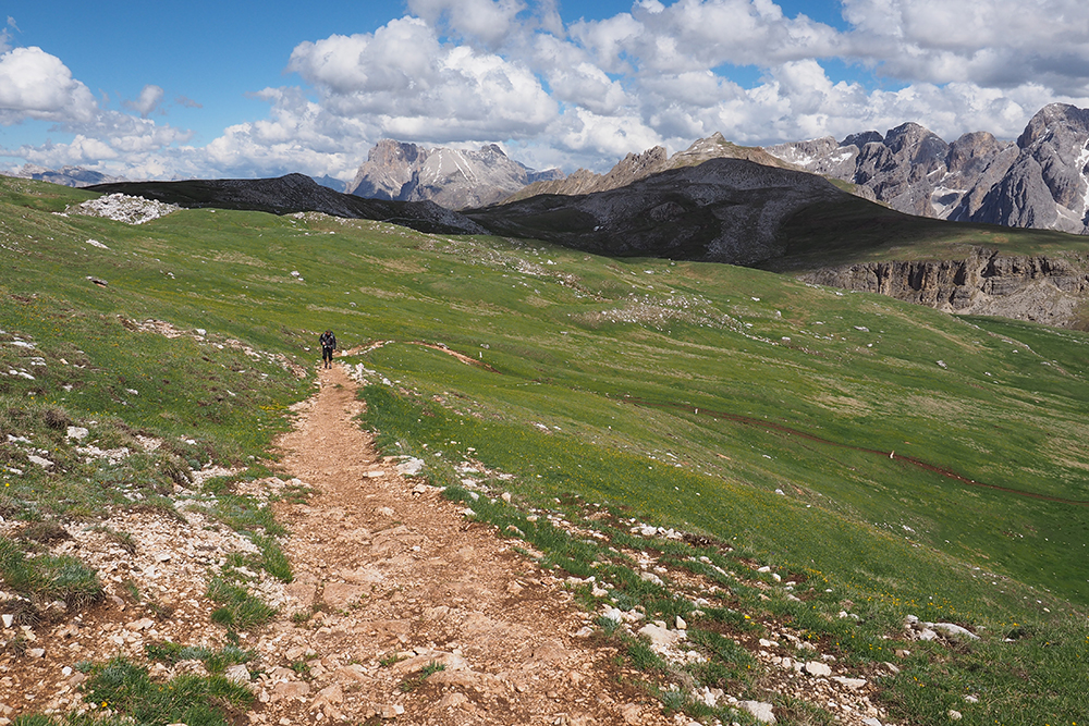 Ein breiter Wanderweg, der flach durch eine Berglandschaft führt