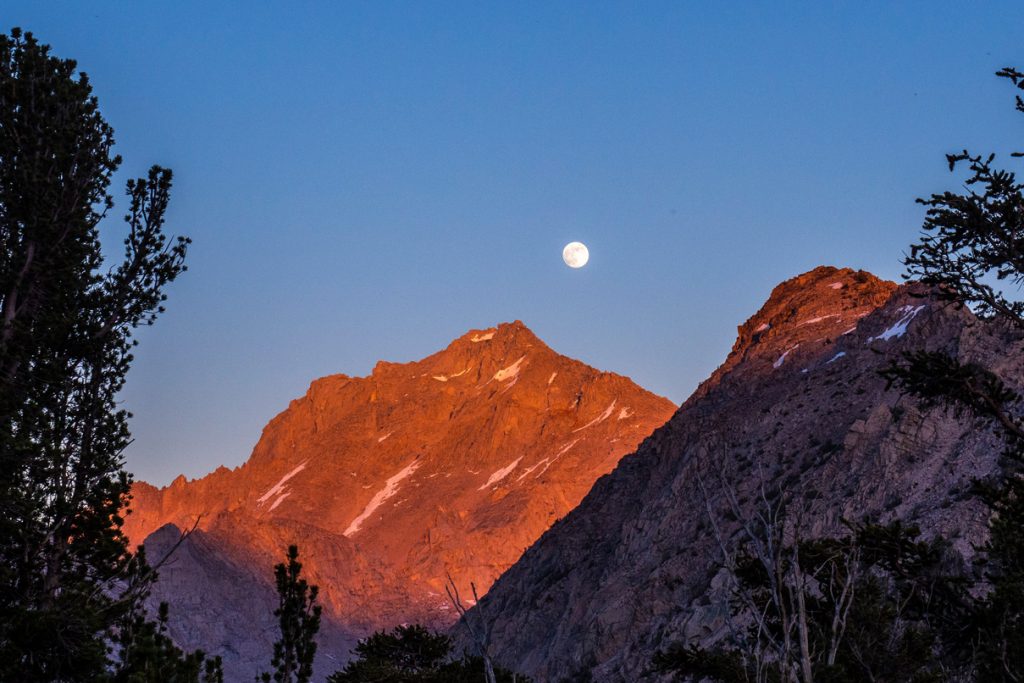 Mondaufgang über einer rot erleuchteten Bergspitze